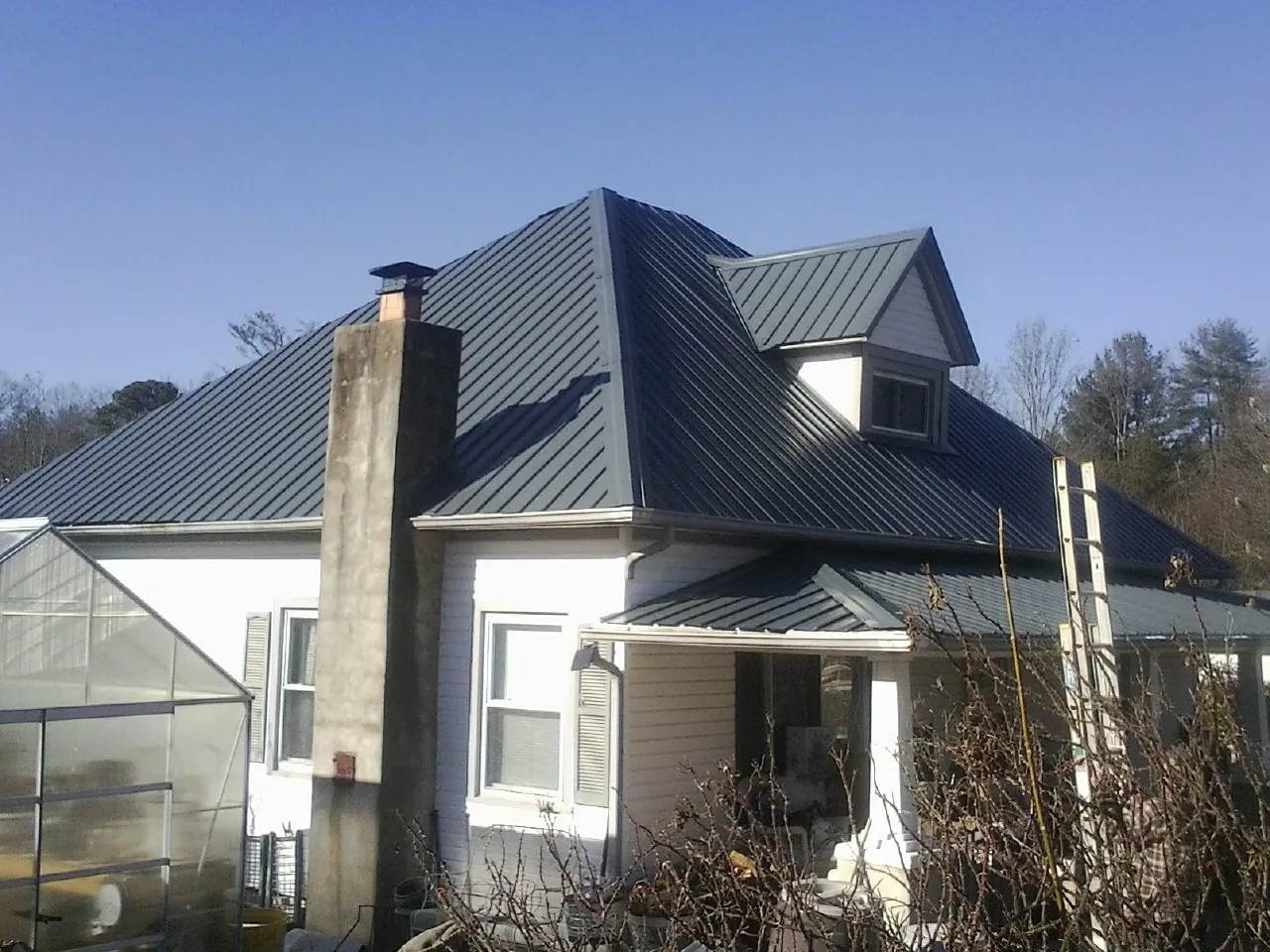 Dark blue standing seam metal roof on a white farmhouse with dormer — Slate & Tile Roof Repair by Roofing Brothers in Whiting