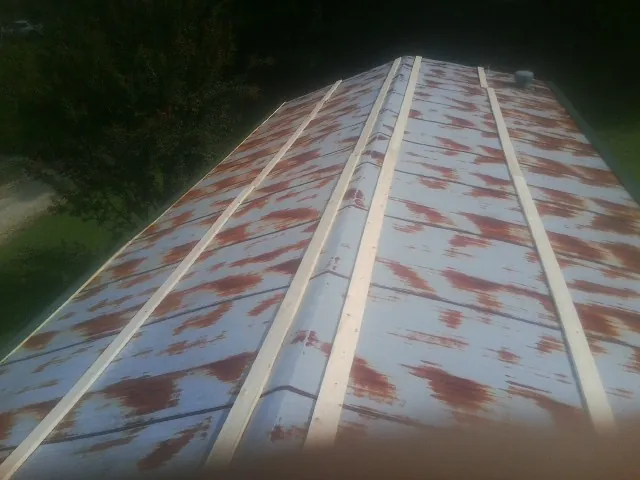 Rusted metal roof panels with new wood purlins before replacement — Storm Damage Roof Repair in Whiting by Roofing Brothers