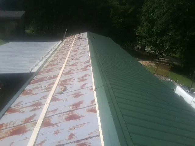 Old rusted panels beside newly installed green metal roofing — Wind Damage Roof Repair by Roofing Brothers in Whiting